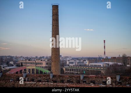Ehemaliger industrieller Ziegelkamin mit wunderschönem Blick auf die Stadt im Hintergrund bei Sonnenuntergang. Ökologie und industrielles Erneuerungskonzept. Stockfoto