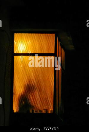 Geheime Geheimnisse. Das Enigma hinter dem Fensterrahmen. Orangefarbenes Licht. Rätsel in der Box. Stockfoto