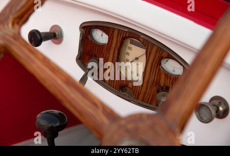 Nahaufnahme des hölzernen Lenkrads und des Armaturenbretts eines Oldtimers mit Tachometer und anderen Anzeigen Stockfoto