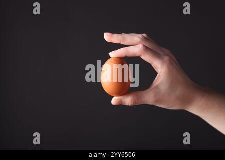 Frau mit rohen Ei auf schwarzem Hintergrund, Nahaufnahme. Leerzeichen für Text Stockfoto