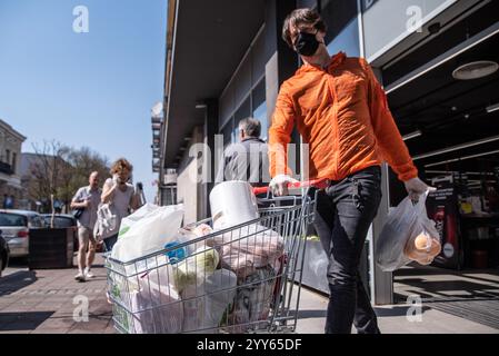 Coronavirus-Pandemieeffekte: Menschen stehen in langen Warteschlangen, um in Panik in den Supermarkt für Lebensmitteleinkäufe zu gehen. Corona-Virus, COVID-19. Stockfoto