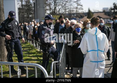 Die Menschen stehen auf der Belgrader Messe vor dem Kontrollpunkt in langen Warteschlangen, während sie auf die Impfung gegen das Coronavirus covid 19 warten. Massenimpfung. Stockfoto
