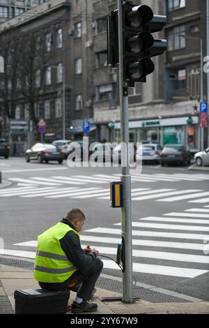 Ein Stadtelektriker arbeitet mit einer Verkabelung, die mit Verkehrsampeln und Sicherheitssignalen verbunden ist. Wartung von Ampeln. Belgrad, Serbien - 12.12.2020 Stockfoto