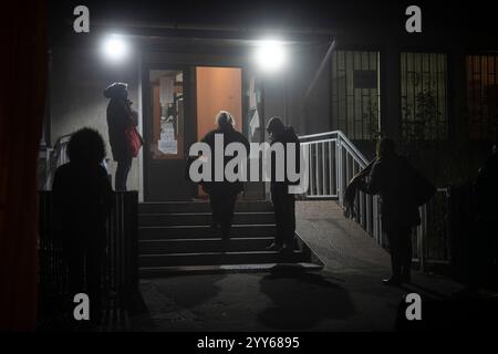 Die Menschen stehen in kalten, nebeligen Winternacht in langen Warteschlangen, während sie darauf warten, ein COVID-19-Testzentrum und ein Krankenhaus zu betreten. Durch Coronavirus verursacht - COVID-19 Stockfoto