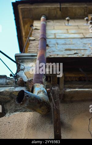 Nahaufnahme eines verrosteten alten Dachrinnenrohrs, an einem alten beschädigten Haus. Stockfoto