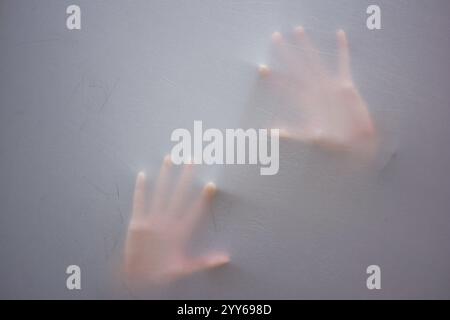 Kopf und Handabdruck einer Frau, die hinter Stoff, erhobenen Händen und weit geöffnetem Mund erstickt. Mystery-Konzept. Schattenverwischung einer schreienden Frau. Touchi Stockfoto