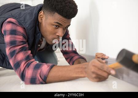 Mann, der mit einem Hammer die Sockelleiste passt Stockfoto