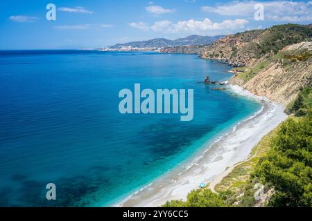 Blaues Wasser und malerische Klippen umgeben einen ruhigen Strand in der Nähe von Nerja, Spanien. Stockfoto