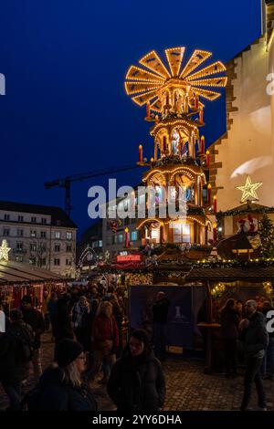 Basel, Schweiz - 5. Dezember 2024: Traditionelle Weihnachtsmarktpyramide am Abend auf dem Barfusserplatz mit festlichen Lichtern Stockfoto