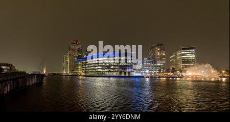 Helle Lichter der modernen Architektur beleuchten die Salford Waterfront in Media City und zeigen eine lebhafte Stadtlandschaft bei Nacht. Stockfoto