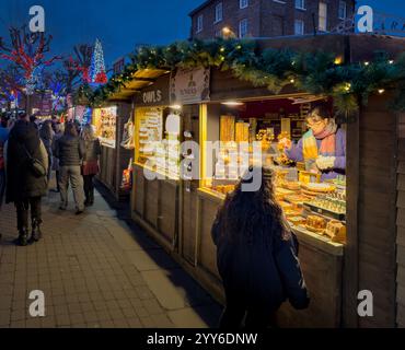 Besucher genießen Shopping und bummeln in den festlichen Ständen des Yorker Weihnachtsmarktes, während die Dämmerung mit Lichtern und Weihnachtsstimmung einbricht. Stockfoto