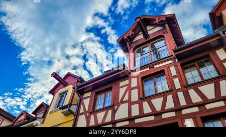 Schöne und charmante mittelalterliche Holzrahmenhäuser mit einem Lastkran auf dem Dach vor dem Hintergrund des blauen Himmels mit weißen Wolken Stockfoto