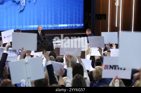 Moskau, Russland. Dezember 2024. Der russische Präsident Wladimir Putin, Mitte, will während der jährlichen Pressekonferenz und der Call-in-Show einen Reporter mit Alexandra Suworova, links, und Dmitry Kulko, rechts, in Gostinny Dvor, anrufen. 19. Dezember 2024 in Moskau, Russland. Quelle: Vyacheslav Prokofyev/Kreml Pool/Alamy Live News Stockfoto