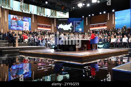 Moskau, Russland. Dezember 2024. Der russische Präsident Wladimir Putin sitzt an einem Tisch mit der Gastgeberin Alexandra Suworova, rechts, und Dmitri Kulko, links, während der jährlichen Pressekonferenz und Call-in-Show in Gostinny Dvor am 19. Dezember 2024 in Moskau. Quelle: Alexander Kazakov/Kreml Pool/Alamy Live News Stockfoto