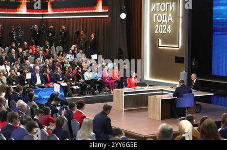 Moskau, Russland. Dezember 2024. Der russische Präsident Wladimir Putin, rechts, hört eine Frage mit den Gastgebern Alexandra Suworova, links, und Dmitri Kulko, Mitte, während der jährlichen Pressekonferenz und Call-in-Show in Gostinny Dvor, 19. Dezember 2024 in Moskau, Russland. Quelle: Gavriil Grigorov/Kreml Pool/Alamy Live News Stockfoto