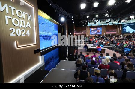 Moskau, Russland. Dezember 2024. Der russische Präsident Wladimir Putin, Mitte, hört eine Frage mit den Gastgebern Alexandra Suworova, links, und Dmitri Kulko, rechts, während der jährlichen Pressekonferenz und Call-in-Show in Gostinny Dvor, 19. Dezember 2024 in Moskau, Russland. Quelle: Vyacheslav Prokofyev/Kreml Pool/Alamy Live News Stockfoto