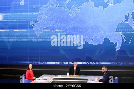 Moskau, Russland. Dezember 2024. Der russische Präsident Wladimir Putin, Mitte, hört eine Frage mit den Gastgebern Alexandra Suworova, links, und Dmitri Kulko, rechts, während der jährlichen Pressekonferenz und Call-in-Show in Gostinny Dvor, 19. Dezember 2024 in Moskau, Russland. Quelle: Gavriil Grigorov/Kreml Pool/Alamy Live News Stockfoto