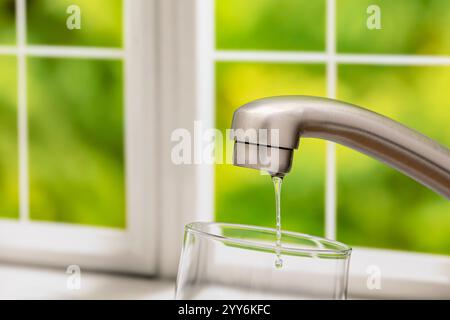 Wasser tropft aus dem Küchenarmatur. Wassereinsparung, Knappheit und sicheres Trinkwasser. Stockfoto