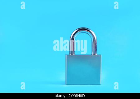 Großes Vorhängeschloss aus Metall auf klassischem blauem Hintergrund in einem Studio. Sicherheits- und Minimalismus-Konzept mit Kopierraum für Text oder Design Stockfoto