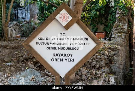 Kayakoy, Mugla, Türkei - 12. Oktober 2024: Beschilderung der Geisterstadt Kayakoy. Verlassenes griechisches Dorf mit zerbröckelnden Steinhäusern, historischen Ruinen und einem Haunti Stockfoto