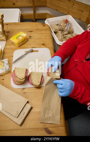 Hamburg, Deutschland. Dezember 2024. Ein freiwilliges Mitglied des Deutschen Roten Kreuzes (DRK) packt Brotlaibe ein, die später an Bedürftige in der Innenstadt verteilt werden. Quelle: Georg Wendt/dpa/Alamy Live News Stockfoto