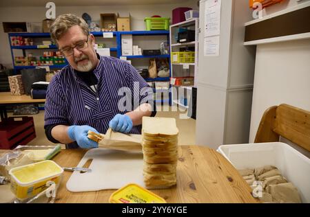 Hamburg, Deutschland. Dezember 2024. Oliver Tomsky, ein ehrenamtliches Mitglied des Deutschen Roten Kreuzes (DRK), packt Brotlaibe, die später an bedürftige Menschen in der Innenstadt verteilt werden. Quelle: Georg Wendt/dpa/Alamy Live News Stockfoto