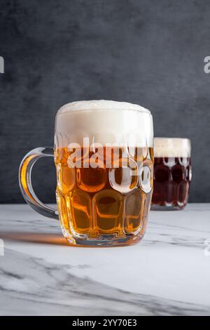 Köstliche Pale Ale- und Amber Ale-Biergetränke mit großen Schaumköpfen in traditionellen und klassischen Gläsern Stockfoto