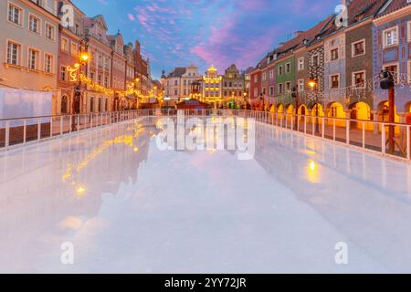 Blick auf farbenfrohe historische Stadthäuser mit leuchtenden Arkaden, die sich im Winter auf einer Eislaufbahn auf dem Alten Marktplatz von Posen, Polen, spiegeln Stockfoto