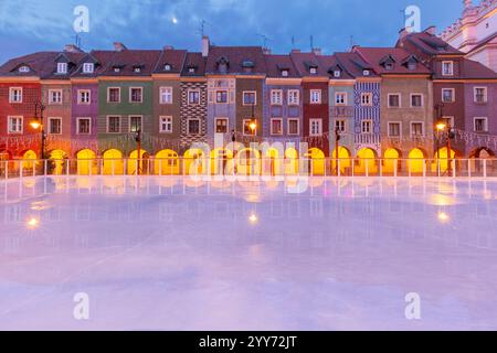 Blick auf farbenfrohe historische Stadthäuser mit leuchtenden Arkaden, die sich im Winter auf einer Eislaufbahn auf dem Alten Marktplatz von Posen, Polen, spiegeln Stockfoto