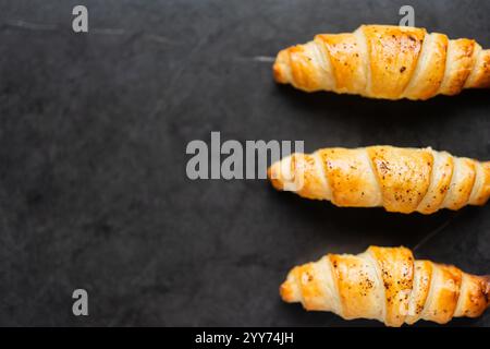 Köstliche knusprige drei Croissants auf schwarzem Hintergrund. Ein leiser Schuss Essen. Stockfoto