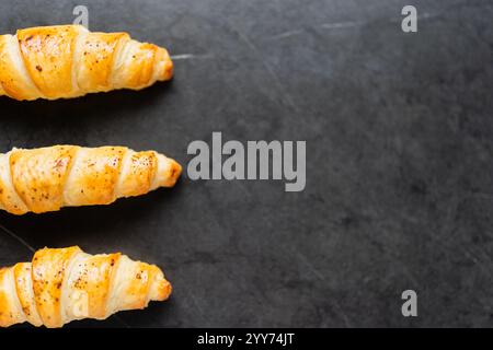 Köstliche knusprige drei Croissants auf schwarzem Hintergrund. Ein leiser Schuss Essen. Stockfoto