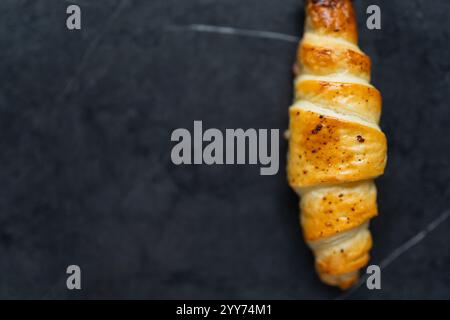 Köstliches knuspriges Croissant auf schwarzem Hintergrund. Ein leiser Schuss Essen. Stockfoto