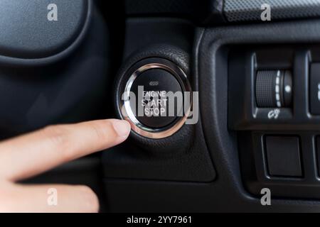 Frau, die am Fahrzeug die Taste Start/STOP Engine drückt. Nahaufnahme von jemandem, der versucht, das Auto per Startknopf anzuzünden, Detailaufnahme des jungen Busins Stockfoto