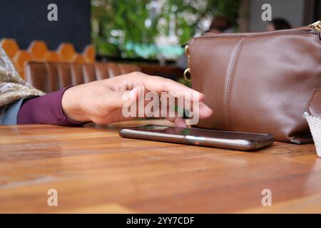 Eine Hand, die das Handy auf dem Tisch abnimmt. Stockfoto