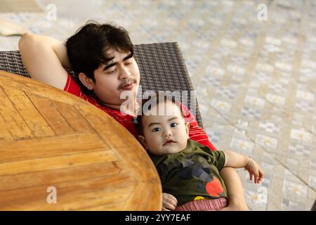 Entspannter Vater kuschelt mit dem Jungen. Freudige Bindung zwischen Vater und Baby. Stockfoto