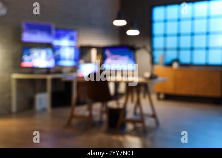 Verschwommener Blick auf das dunkle Büro mit Händlerpulten und leuchtenden Lampen bei Nacht Stockfoto