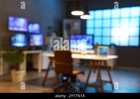 Verschwommener Blick auf das dunkle Büro mit Händlerpulten und leuchtenden Lampen bei Nacht Stockfoto