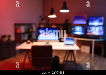 Verschwommener Blick auf ein dunkles Büro mit Händlertischen und leuchtenden Lampen bei Nacht Stockfoto