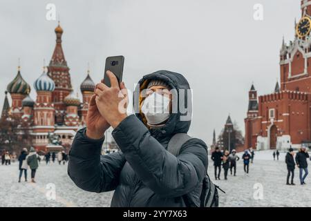 Ein Mann mit Maske macht ein Foto auf seinem Handy auf dem Roten Platz. Hochwertige Fotos Stockfoto