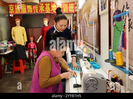 (241220) -- DONGXING, 20. Dezember 2024 (Xinhua) -- Fan Wenying (hinten), immaterielles Kulturerbe Erbe von Jing Kostümmacherkunst, spricht mit einem Mitarbeiter in Dongxing, südchinesischer Autonomen Region Guangxi Zhuang, 16. Dezember 2024. Die ethnische Gruppe der Jing ist die einzige maritime ethnische Gruppe in China, wobei die meisten ihrer Mitglieder auf den drei Inseln vor der Küste von Dongxing in Guangxi an Vietnam angrenzenden Grenzregionen leben. Als eine der kleinsten Minderheitengruppen Chinas sind die Jing derzeit weniger als 30.000. In der Vergangenheit verließen sich die Jing-Leute vollständig auf die traditionelle Fischerei, um ihren Lebensunterhalt zu verdienen. B Stockfoto