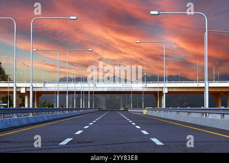 Ein atemberaubender landschaftlich reizvoller Highway unter einem dramatischen und wunderschönen Sonnenuntergang mit lebendigen Farben Stockfoto