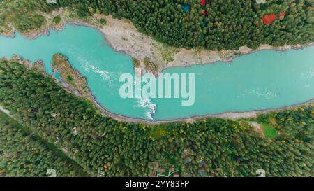 Der türkisfarbene Fluss fließt durch eine üppige grüne Waldlandschaft und schafft eine malerische Szene der Schönheit und Kraft der Natur, die von oben mit einer Drohne gesehen wird Stockfoto