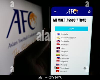 In dieser Fotoabbildung hält eine Person ein Handy mit der Webseite des asiatischen Fußballverbandes (AFC) vor dem Logo. Stockfoto