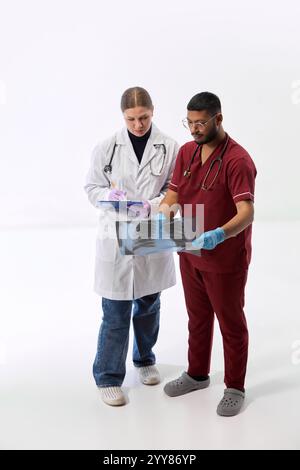 Zwei Mediziner untersuchen Röntgenaufnahmen im Team und schlagen Behandlungen vor weißem Studiohintergrund vor. Luftaufnahme. Stockfoto