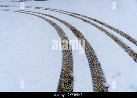 Reifenspuren mit aggressivem Reifenprofil auf frisch fallendem Schnee. Stockfoto