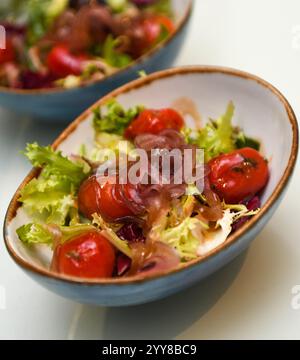 Salat mit Kirschtomaten, Zwiebeln und Salat in einer blauen Schüssel Stockfoto