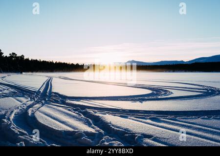 Schneepfade am Sunrise on Frozen Lake Stockfoto