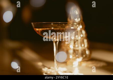 Elegantes Cocktailglas mit goldenem Getränk und festlichen Bokeh-Lichtern Stockfoto