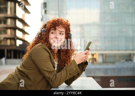 Glückliche Frau, die Musik genießt und Smartphone-App in der Stadt nutzt Stockfoto
