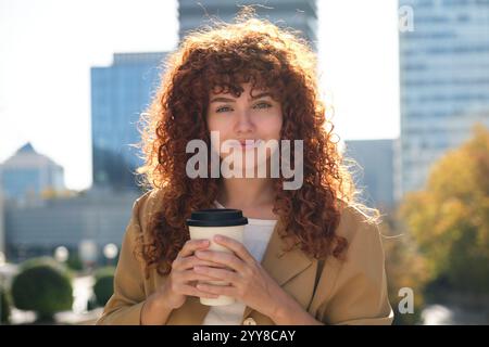 Junge Geschäftsfrau mit wiederverwendbarer Kaffeetasse in urbaner Umgebung Stockfoto